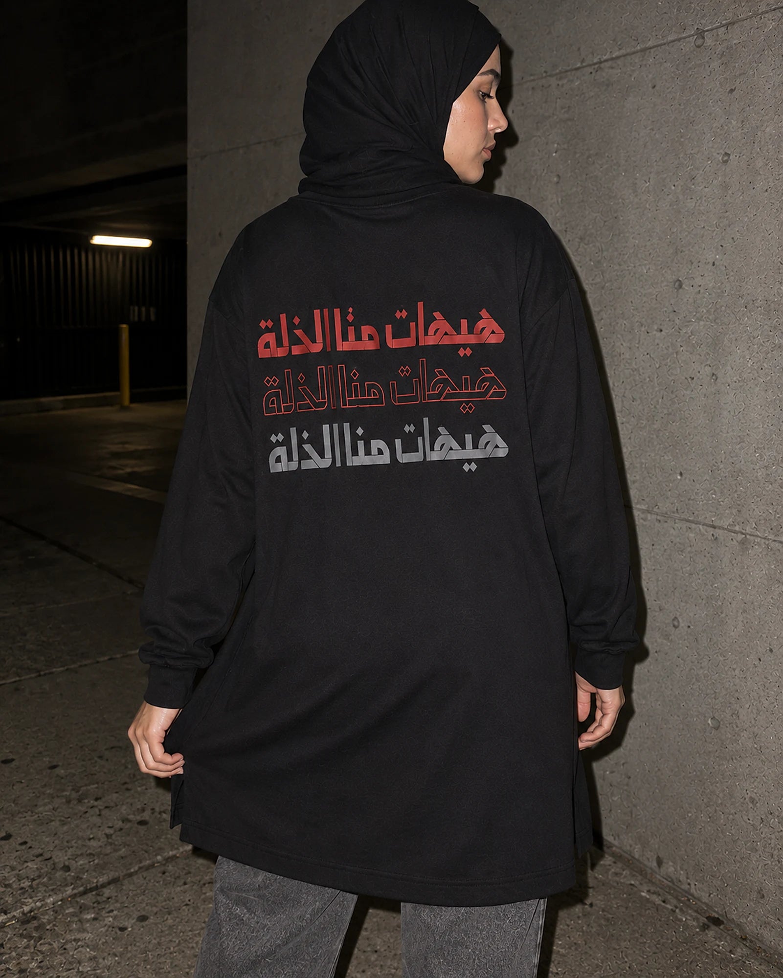 Never to Humiliation women's shirt in a parking garage